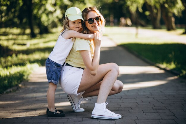 Mujer joven con pequeña hija caminando en el parque