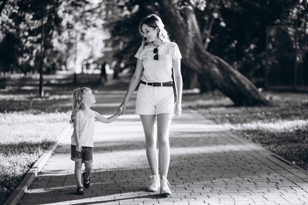 Mujer joven con pequeña hija caminando en el parque