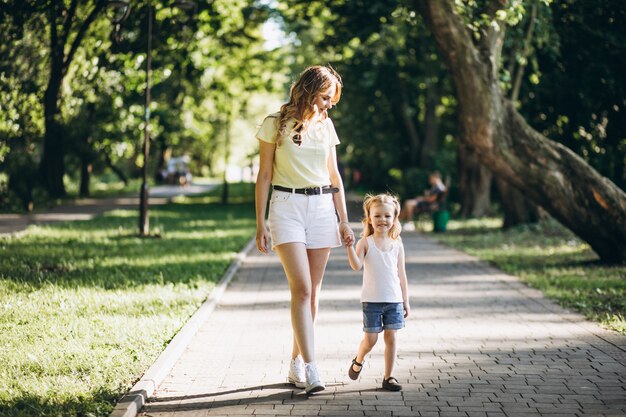 Mujer joven con pequeña hija caminando en el parque