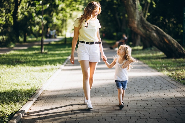 Mujer joven con pequeña hija caminando en el parque