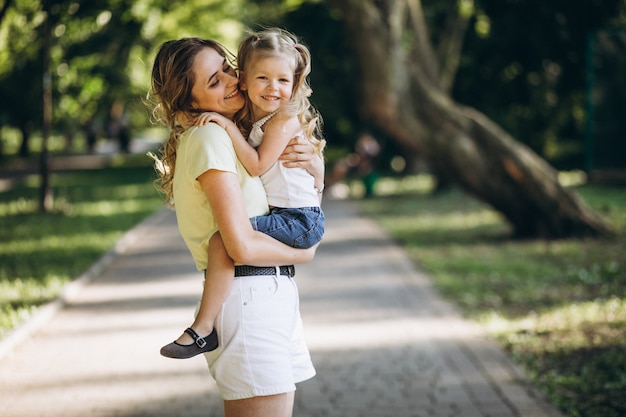 Mujer joven con pequeña hija caminando en el parque