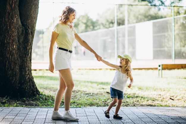 Mujer joven con pequeña hija caminando en el parque