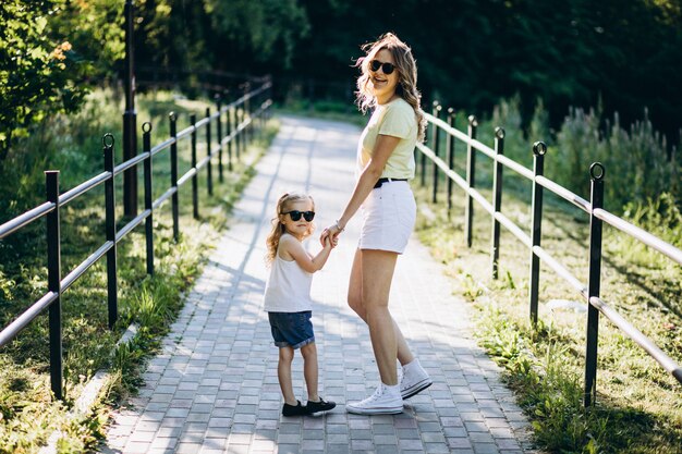 Mujer joven con pequeña hija caminando en el parque