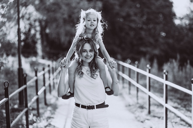 Mujer joven con pequeña hija caminando en el parque