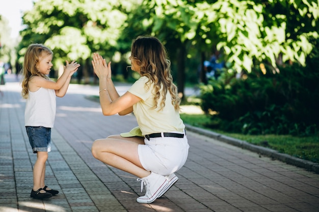 Mujer joven con pequeña hija caminando en el parque