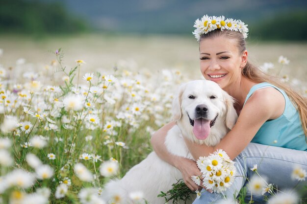 Mujer joven con perro en un campo de manzanilla