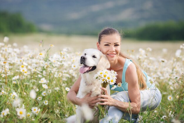 Mujer joven con perro en un campo de manzanilla