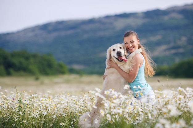 Mujer joven con perro en un campo de manzanilla