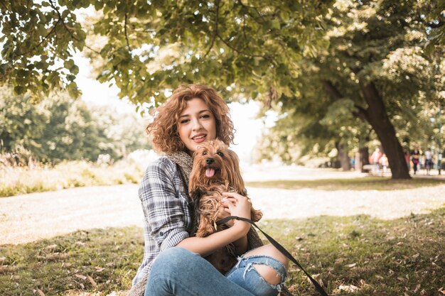 Mujer joven con perro sentado en el parque