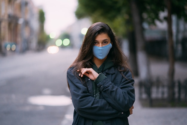 Mujer joven, persona en máscara protectora médica estéril en calle vacía