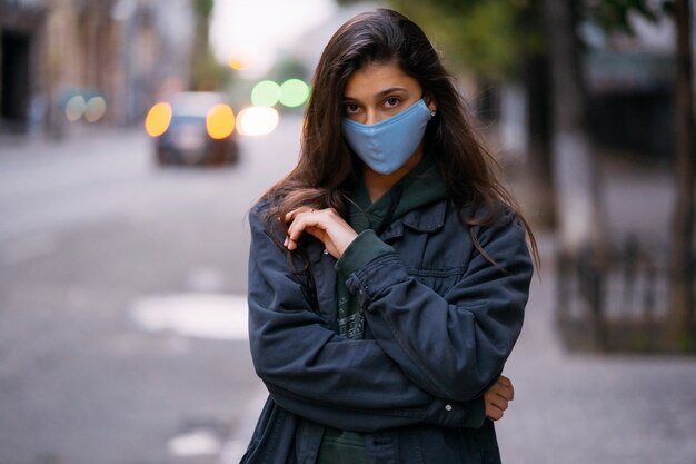 Mujer joven, persona con máscara protectora médica estéril en la calle vacía