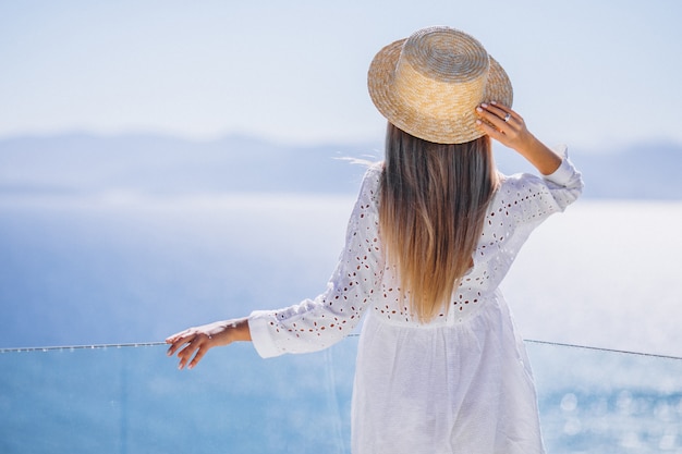 Foto gratuita mujer joven de pie desde atrás y mirando el mar