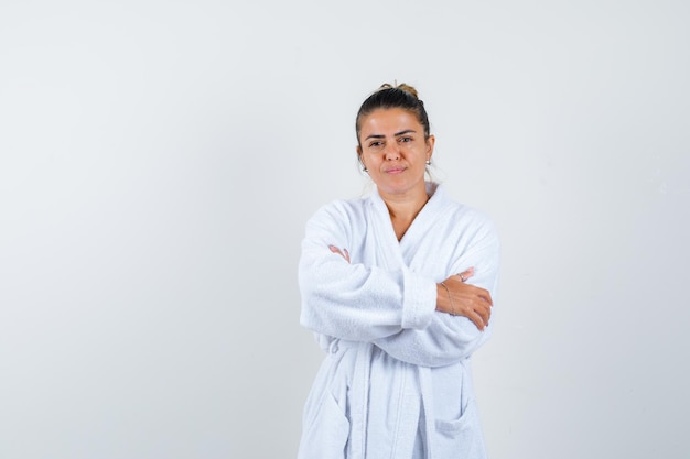 Mujer joven de pie con los brazos cruzados en bata de baño y mirando confiado