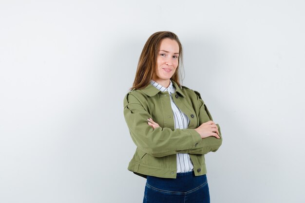 Mujer joven de pie con los brazos cruzados en camisa, chaqueta y mirando confiado. vista frontal.