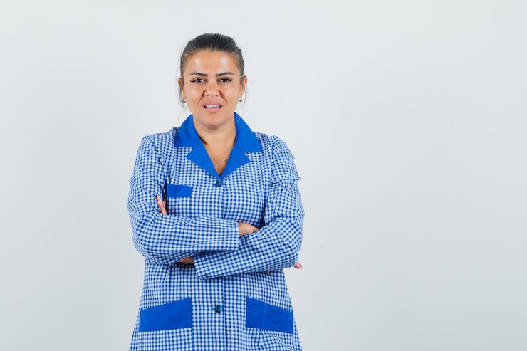Foto gratuito mujer joven de pie con los brazos cruzados en camisa de pijama de cuadros vichy azul y luciendo bonita. vista frontal.