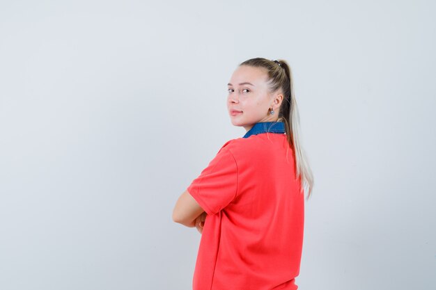 Mujer joven de pie con los brazos cruzados en camiseta y mirando confiado