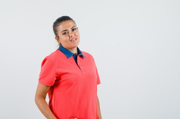 Mujer joven de pie con la espalda recta en camiseta roja y bonita vista frontal.