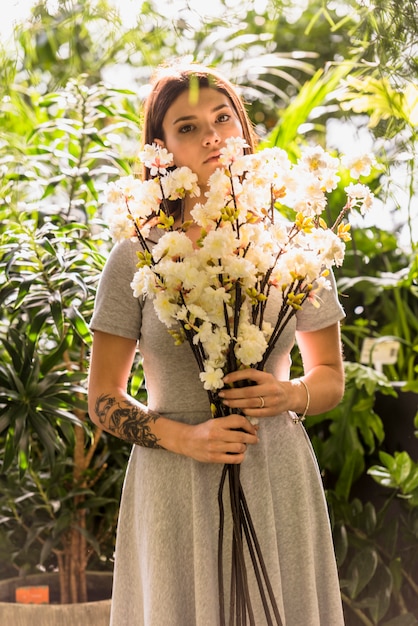 Mujer joven de pie con flores blancas en las manos