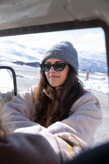 Foto gratuita mujer joven de pie fuera de la autocaravana durante el viaje de invierno