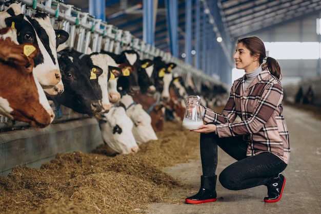 Mujer joven de pie con jarra de leche en el establo