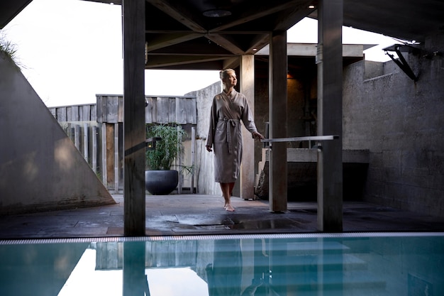 Mujer joven de pie junto a una piscina