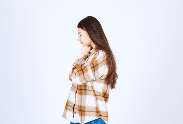 mujer joven de pie de lado en la pared blanca.