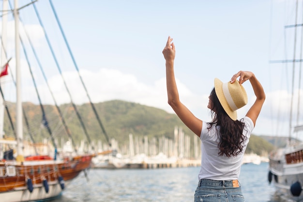 Foto gratuita mujer joven de pie con una mano en un puerto