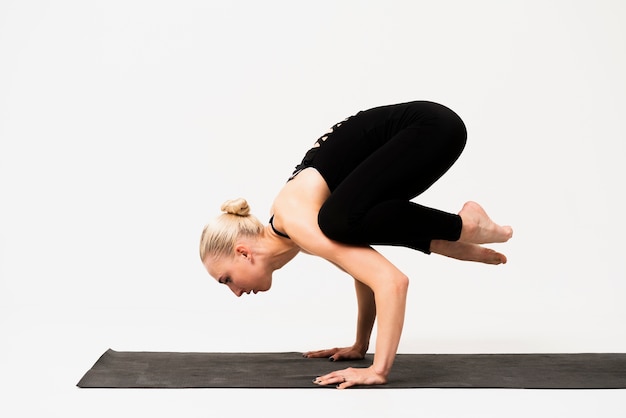 Mujer joven de pie en las manos en la clase de yoga