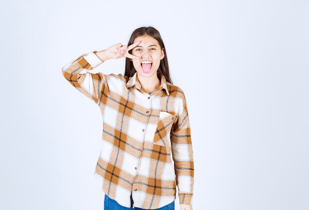 Foto gratuita mujer joven de pie y posando en la pared blanca.