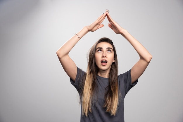 Mujer joven de pie y posando sobre un fondo gris