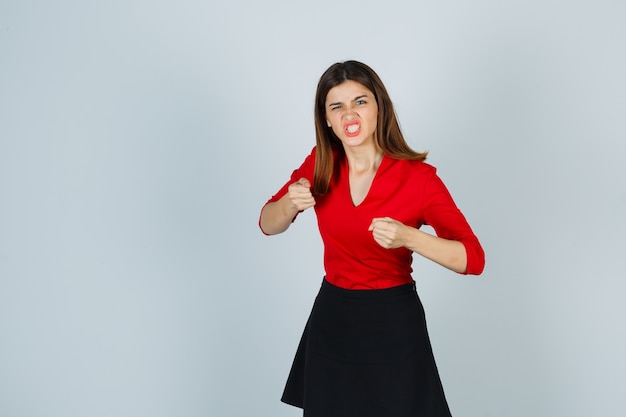 Mujer joven de pie en pose de lucha en blusa roja