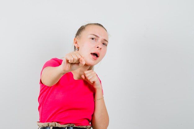 Mujer joven de pie en pose de lucha en camiseta y mirando confiado