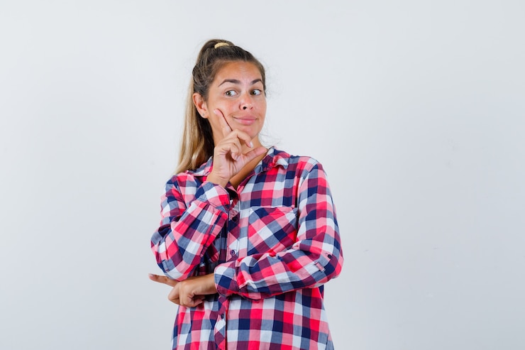 Foto gratuito mujer joven de pie en pose de pensamiento en camisa casual y mirando sensible, vista frontal.