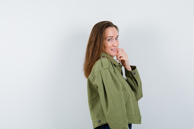 Mujer joven de pie en pose de pensamiento en chaqueta y mirando elegante.