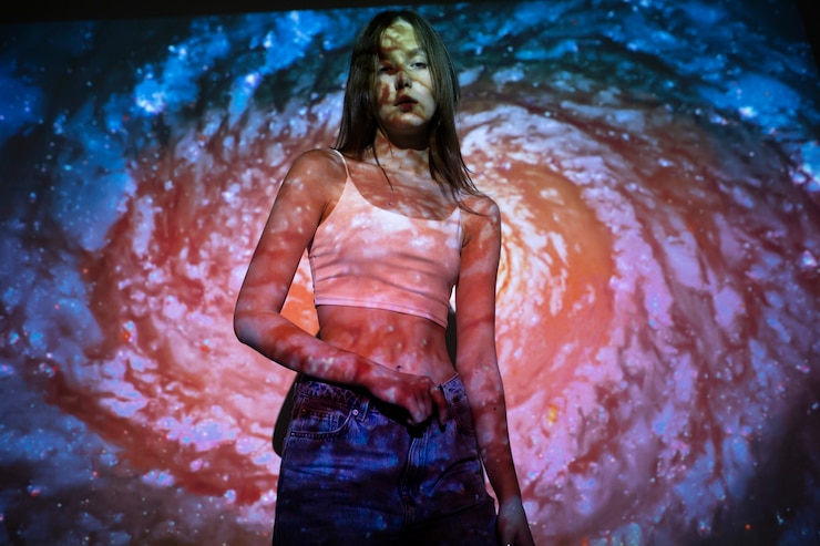 Foto gratuito mujer joven de pie en la proyección de textura del universo