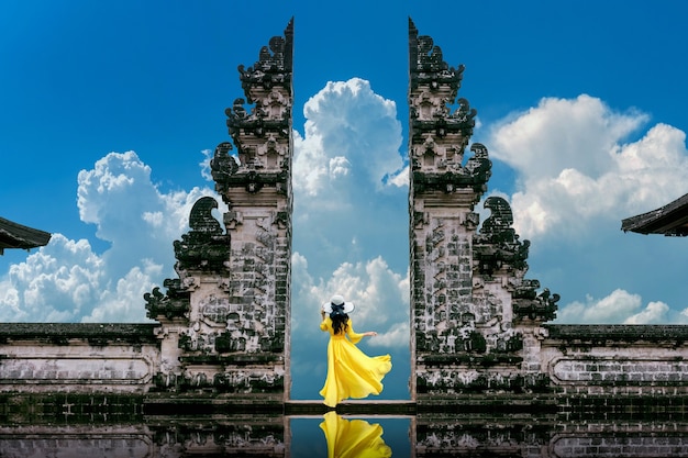 Mujer joven de pie en las puertas del templo en el templo Lempuyang Luhur en Bali, Indonesia. Tono de la vendimia