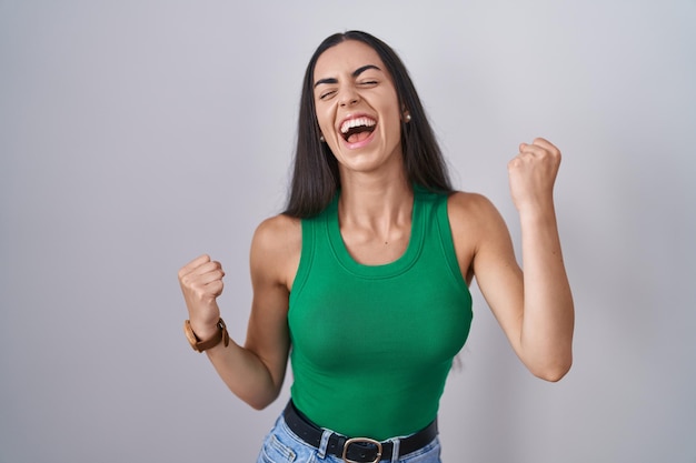 Foto gratuita mujer joven de pie sobre un fondo aislado celebrando sorprendido y asombrado por el éxito con los brazos levantados y los ojos cerrados concepto ganador