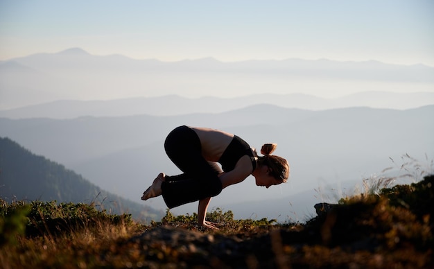 Mujer joven de pie sobre las manos en ejercicio de yoga en la naturaleza