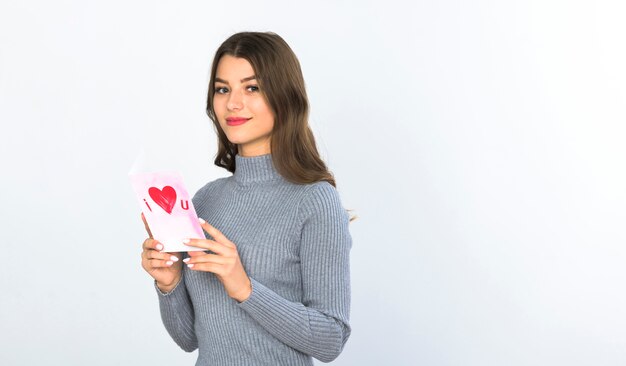 Mujer joven de pie con la tarjeta de felicitación