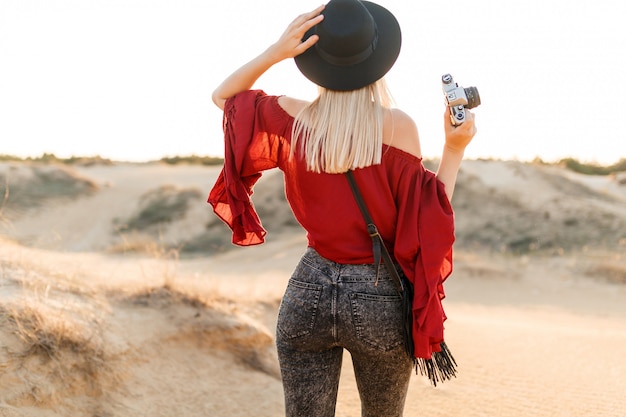 Mujer joven de pie en el valle y mirando el paisaje arenoso del desierto