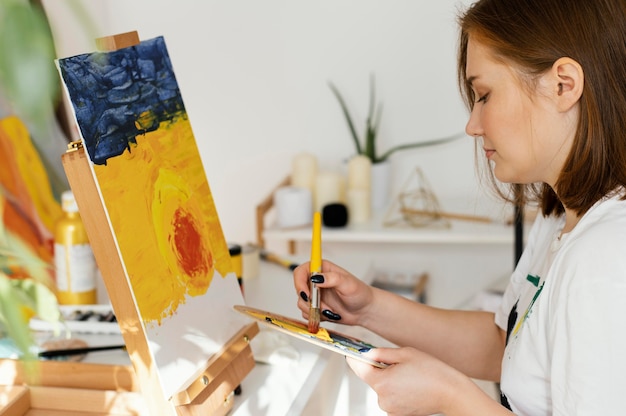 Mujer joven pintando con acrílicos en casa