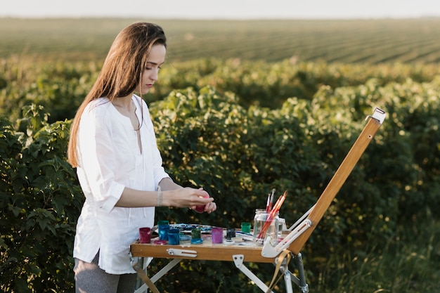 Foto gratuita mujer joven pintando una obra de arte