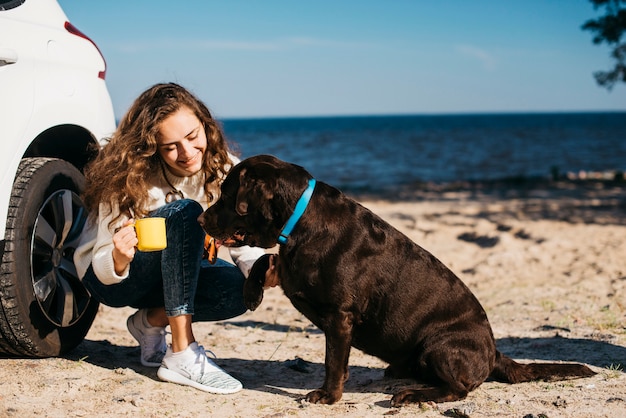 Mujer joven en la playa con su perro