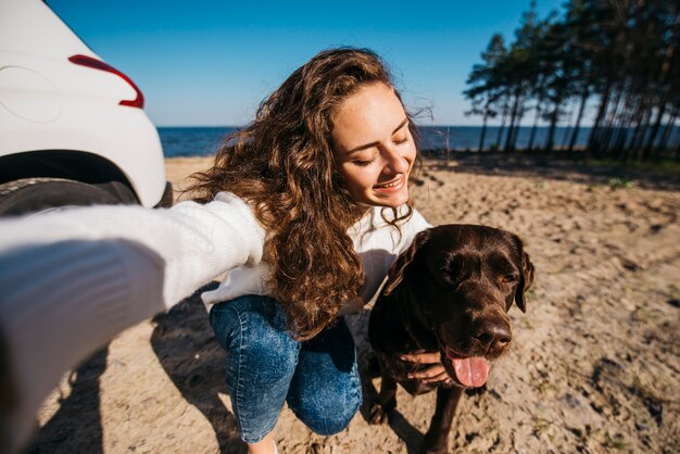 Mujer joven en la playa con su perro