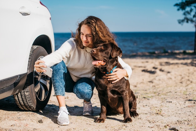 Mujer joven en la playa con su perro