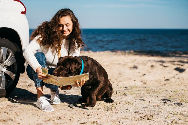 Mujer joven en la playa con su perro