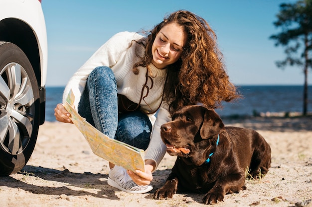 Mujer joven en la playa con su perro