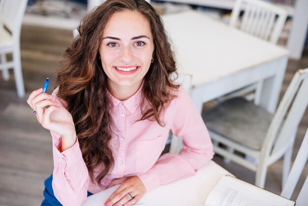 Mujer joven con pluma en la mesa