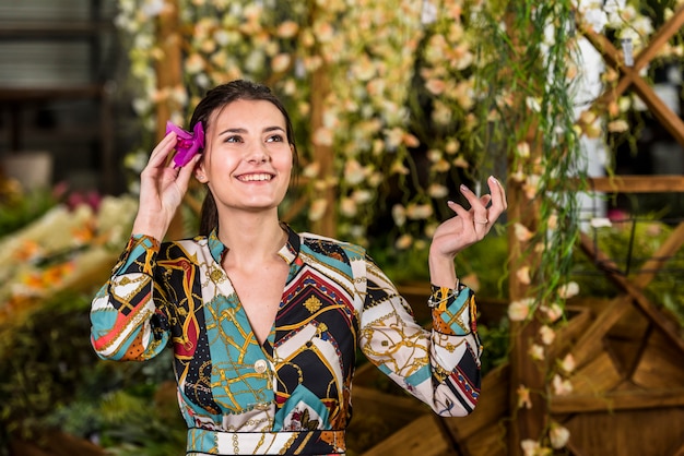 Foto gratuita mujer joven, poniendo, flor, en, pelo