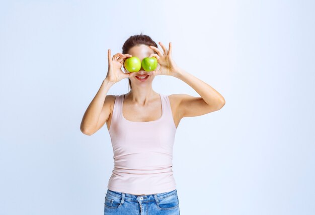 Mujer joven, poniendo, un, manzana verde, a, ella, ojo